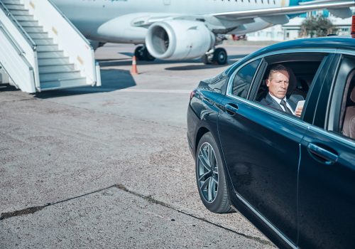 Businessman with smartphone in car at airport